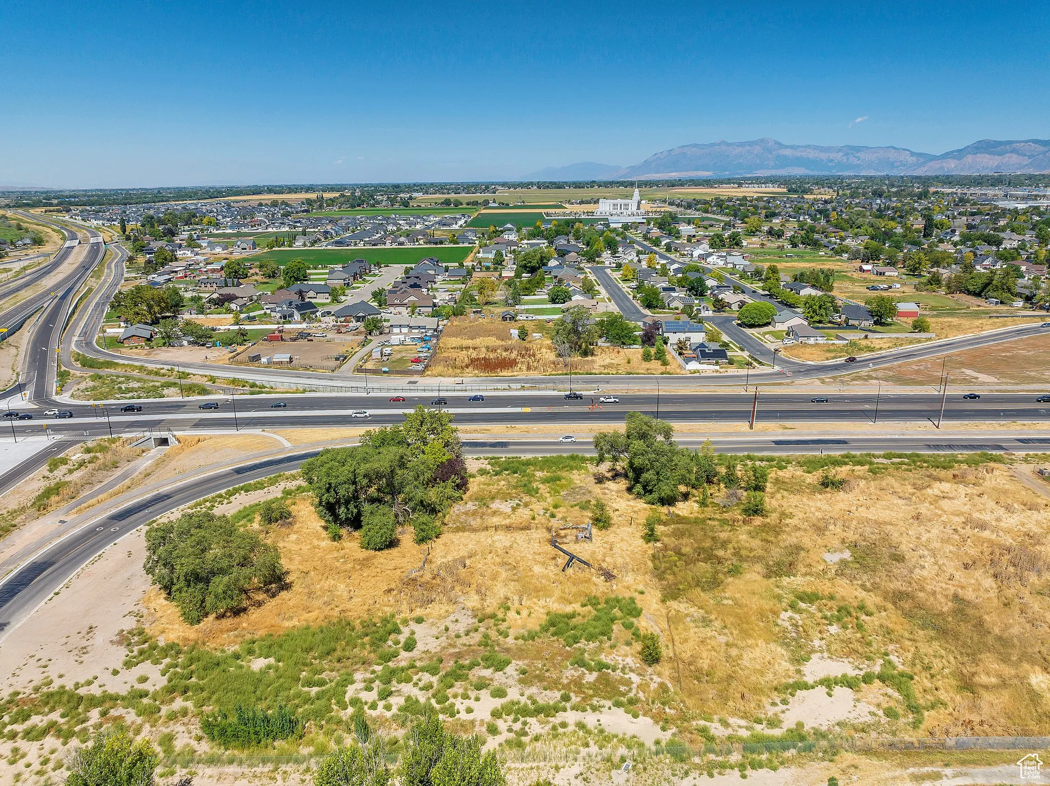 Aerial perspective of suburban area featuring a main thoroughfare and a mountain backdrop