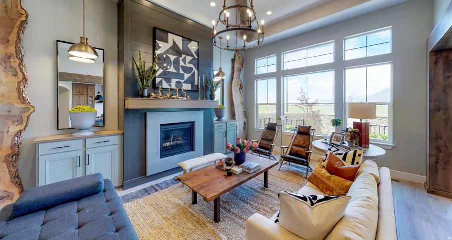 Living room featuring a fireplace, light wood-type flooring, a chandelier, and a towering ceiling