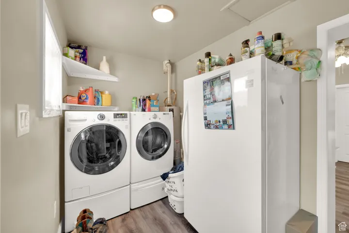Laundry room with washer and dryer, wood finished floors, and attic access