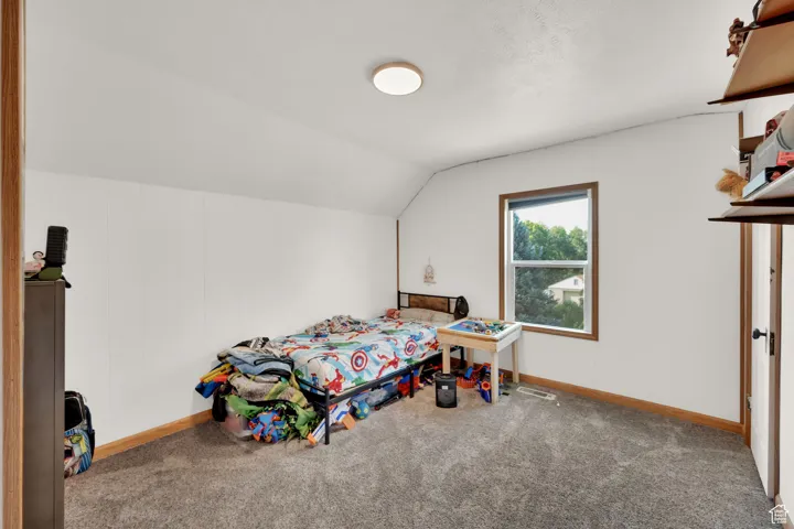 Carpeted bedroom featuring baseboards and lofted ceiling