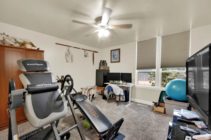 Workout area with ceiling fan and carpet flooring