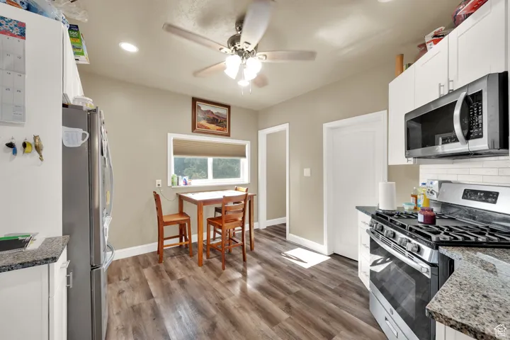 Kitchen with appliances with stainless steel finishes, recessed lighting, ceiling fan, white cabinetry, and wood finished floors