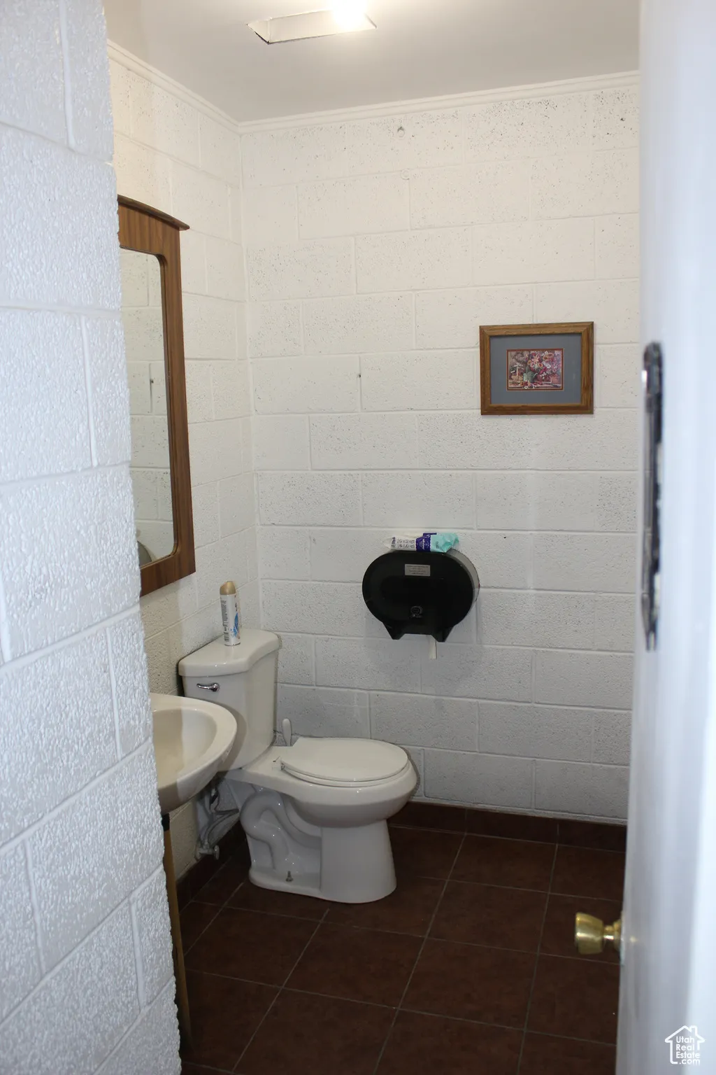 Bathroom featuring tile patterned flooring, ornamental molding, and concrete block wall
