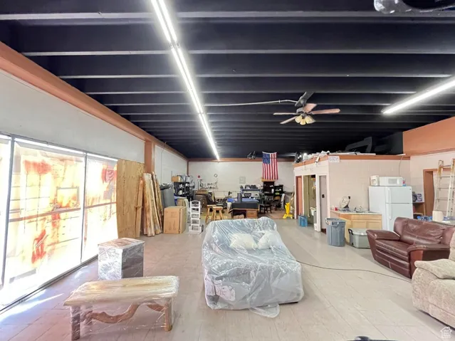 Basement featuring freestanding refrigerator and ceiling fan