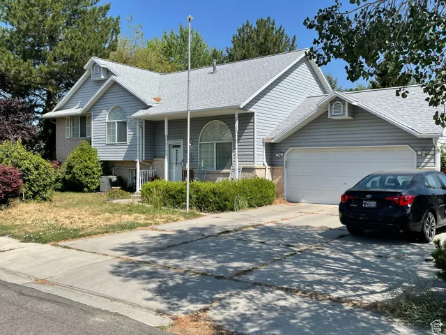 View of front facade with driveway, an attached garage, a shingled roof, and brick siding
