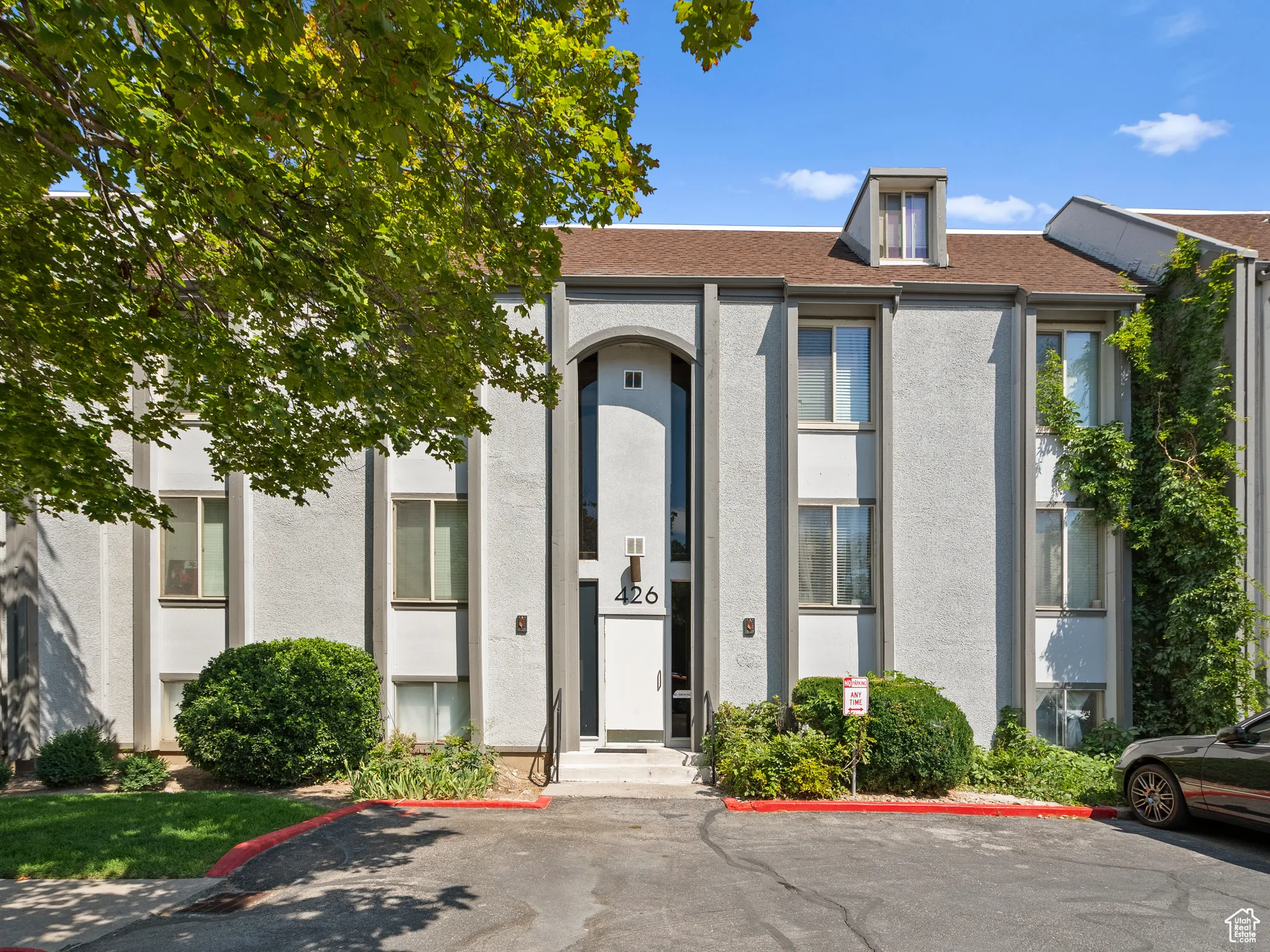 Entrance to property with uncovered parking, stucco siding, and roof with shingles