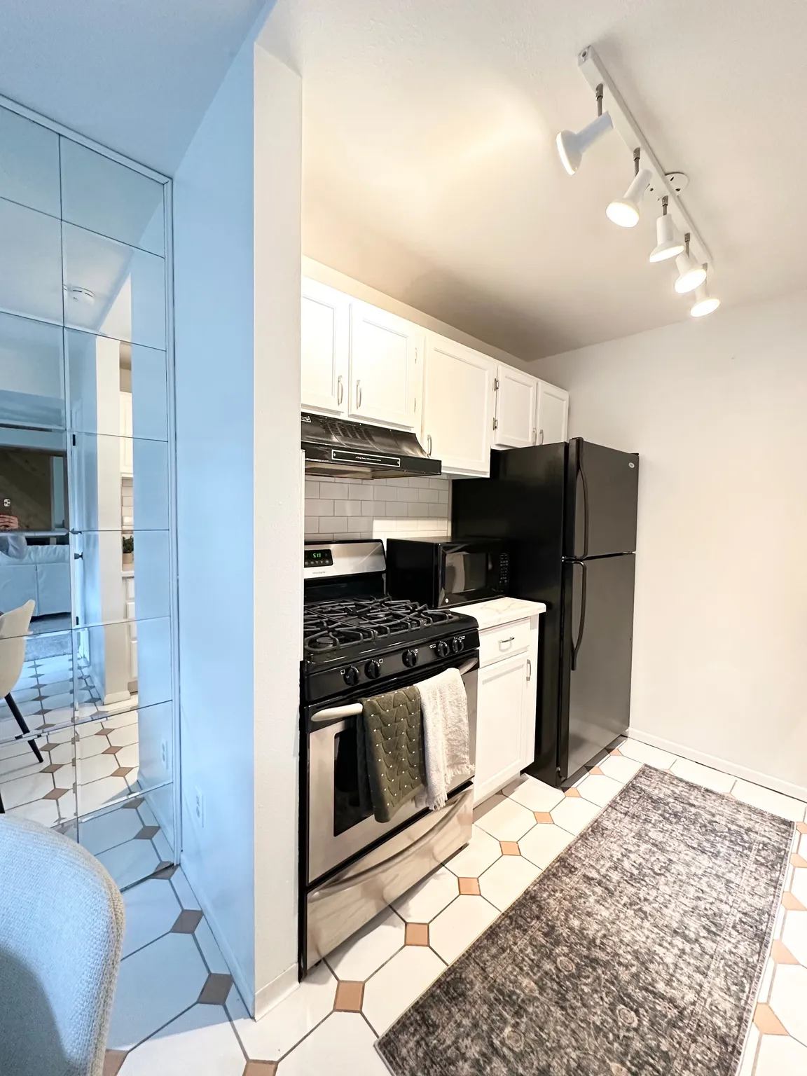 Kitchen with white cabinetry, stainless steel gas range, rail lighting, light countertops, and decorative backsplash