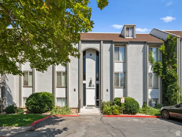 Entrance to property with uncovered parking, stucco siding, and roof with shingles