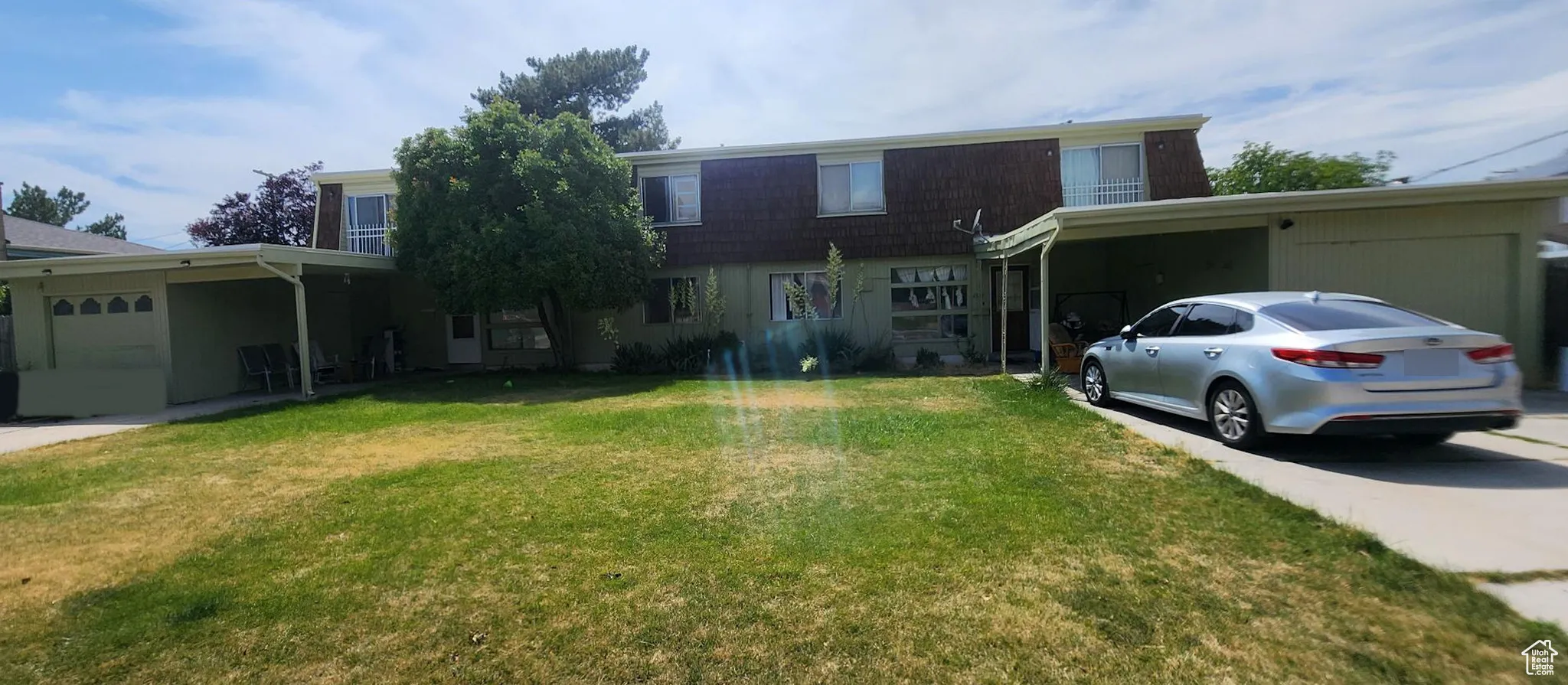 Traditional-style house with driveway, a front lawn, and an attached carport
