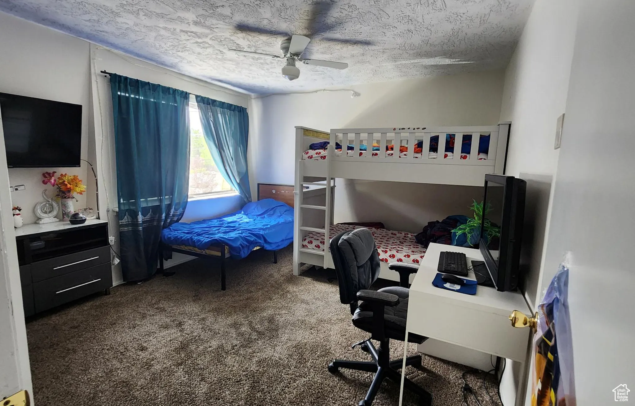 Carpeted bedroom featuring a textured ceiling and ceiling fan
