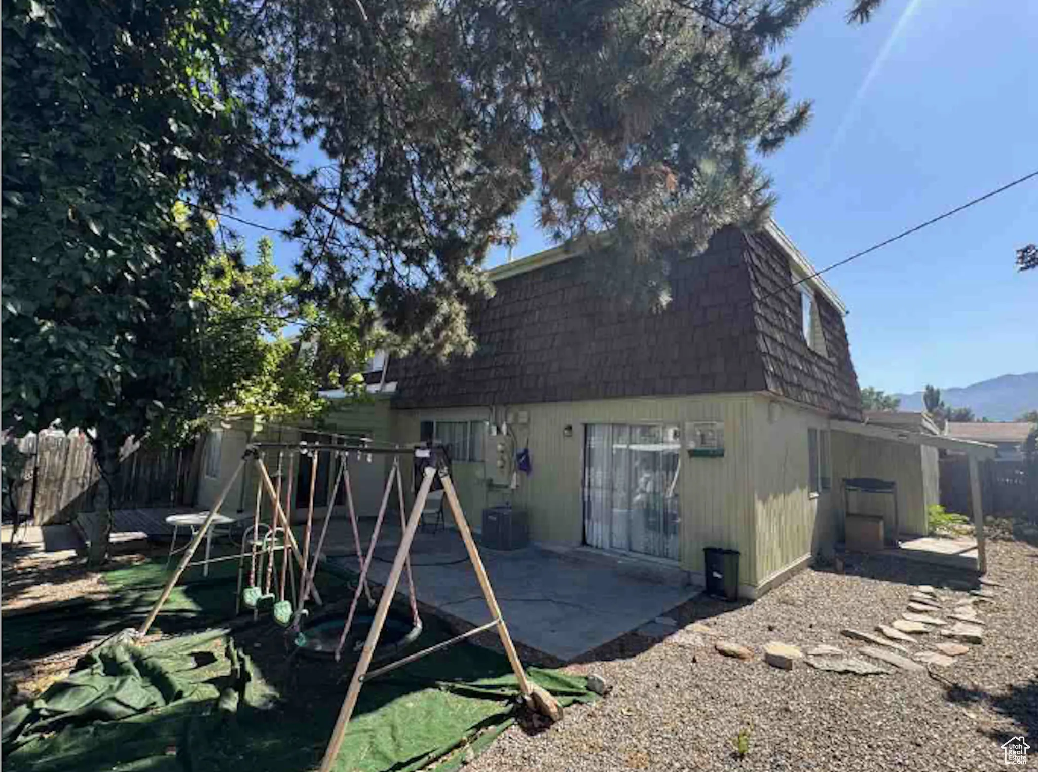 Rear view of property with mansard roof, a patio, and a shingled roof