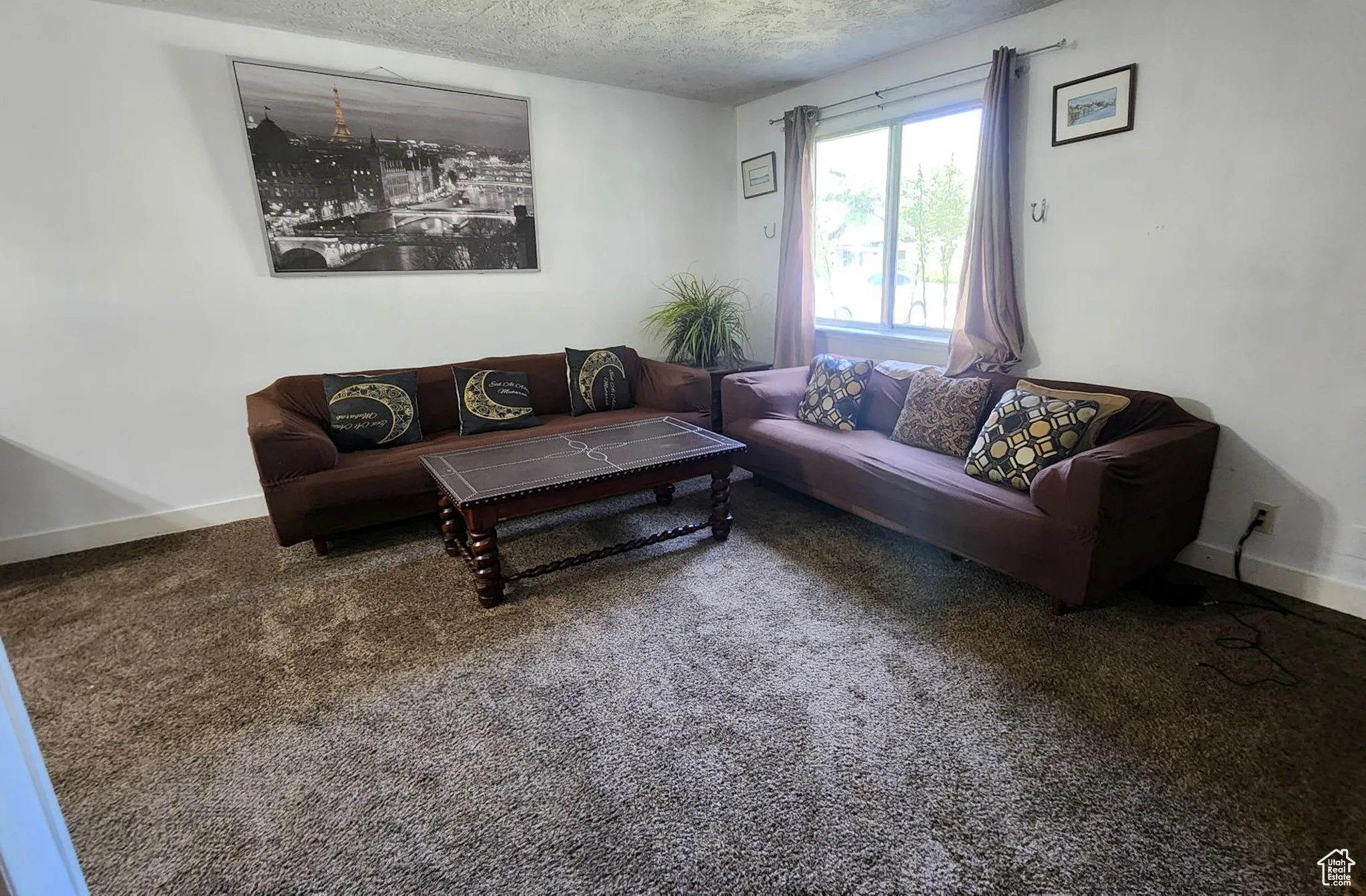 Carpeted living room featuring baseboards and a textured ceiling