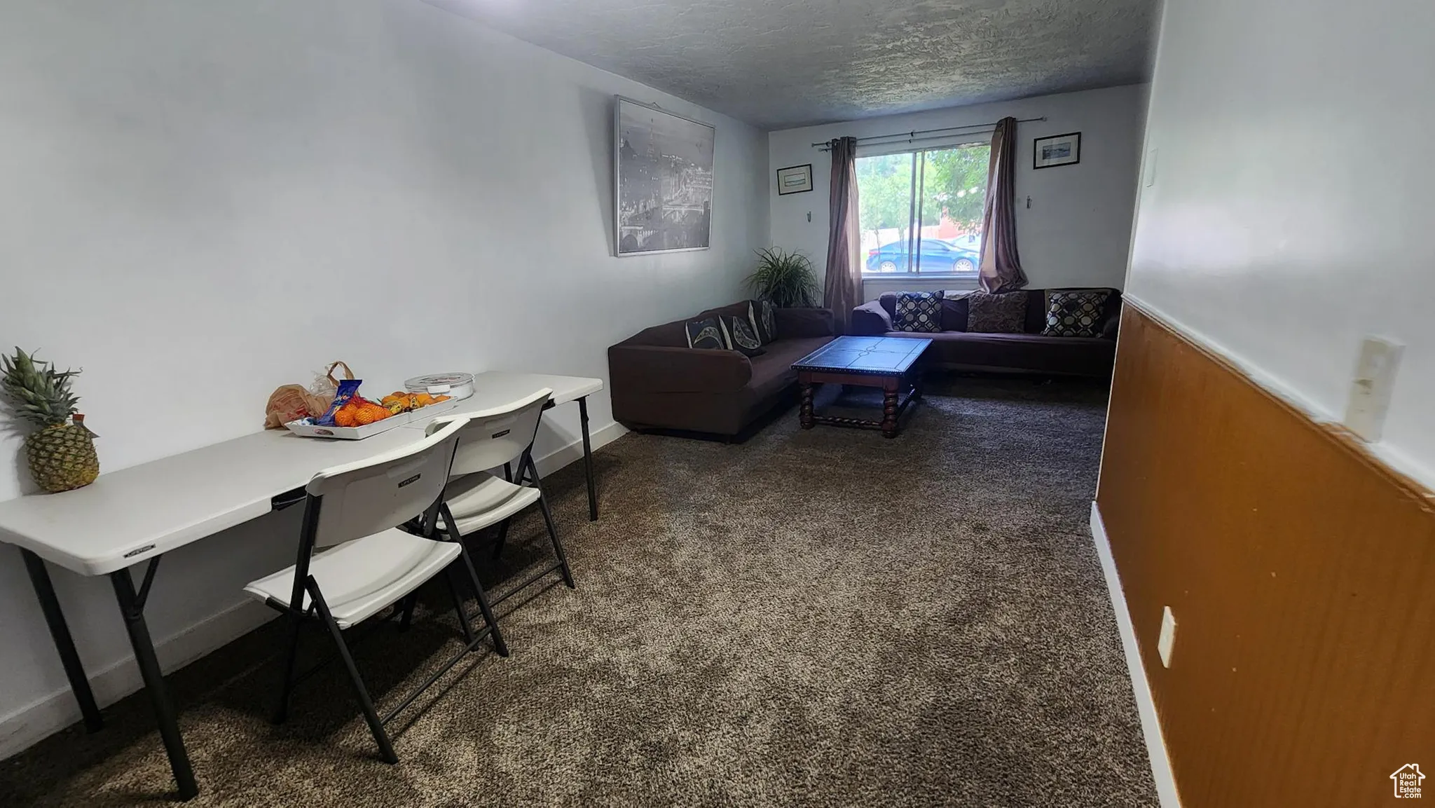 Carpeted living area with a textured ceiling and baseboards