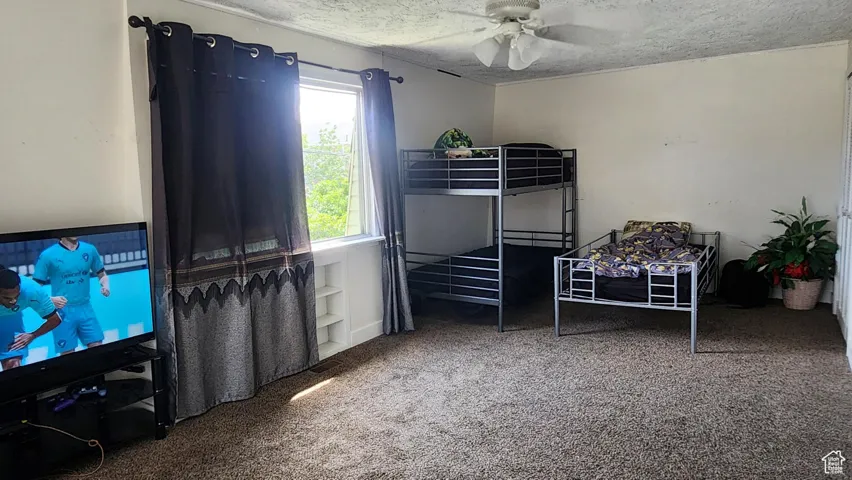 Bedroom featuring a textured ceiling, carpet floors, and ceiling fan