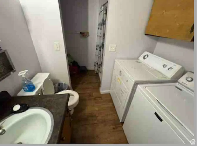 Washroom with washer and dryer and wood finished floors