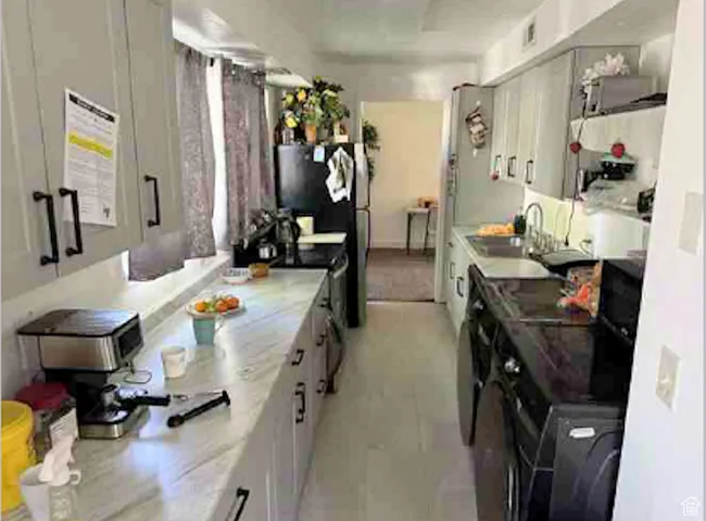 Kitchen featuring range with electric cooktop, light countertops, freestanding refrigerator, and white cabinets