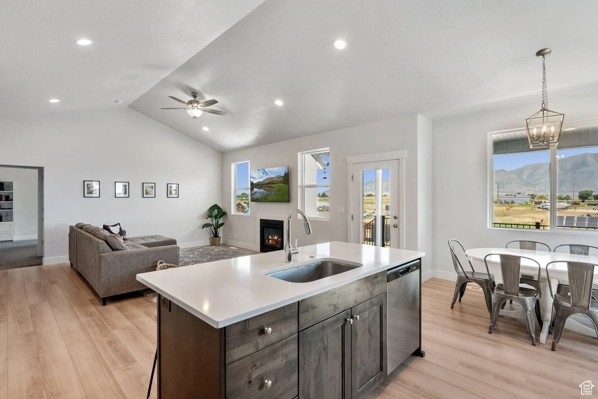 Kitchen featuring open floor plan, a glass covered fireplace, light wood-style floors, light countertops, and lofted ceiling