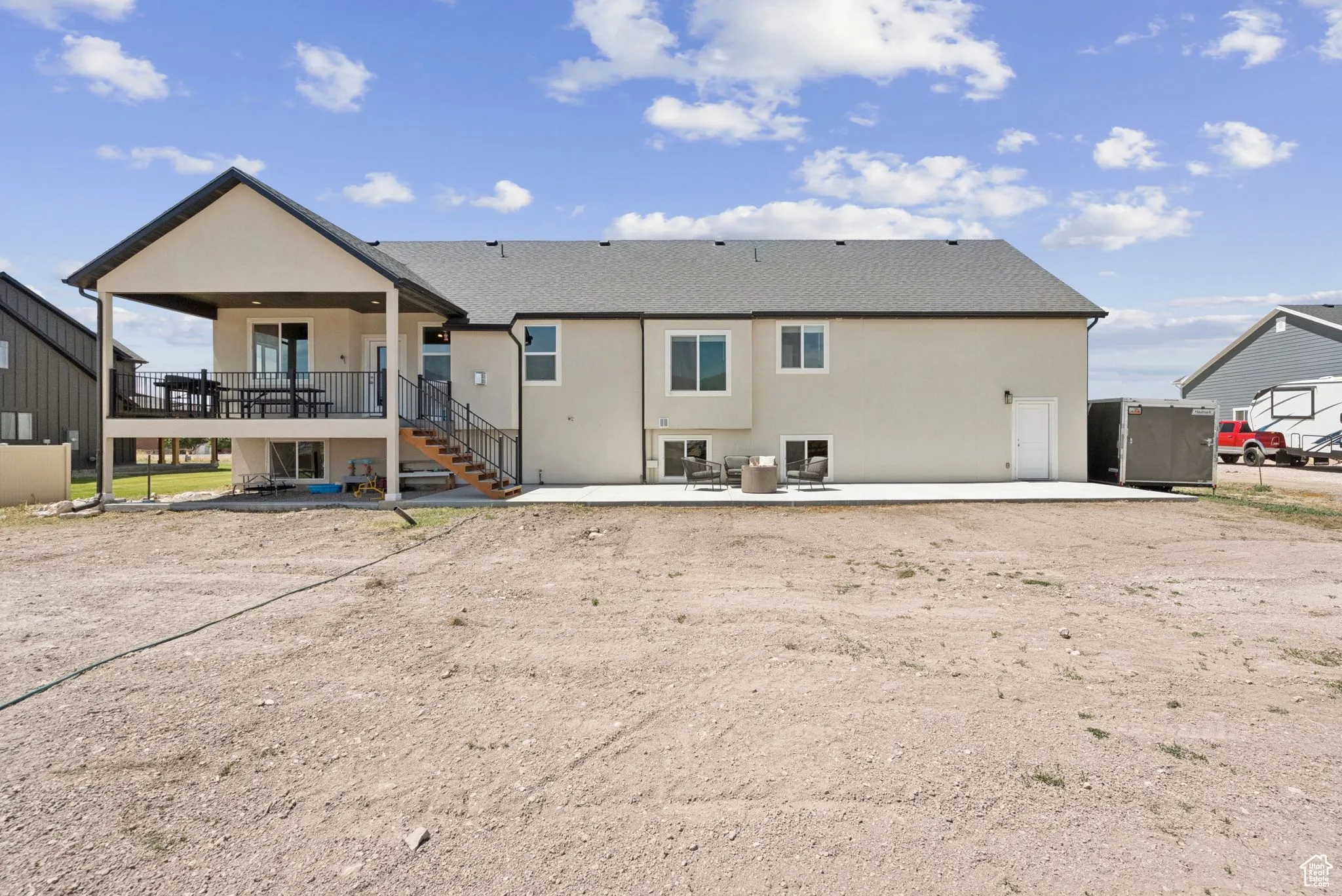 Back of property featuring a patio, stairway, a shingled roof, and stucco siding