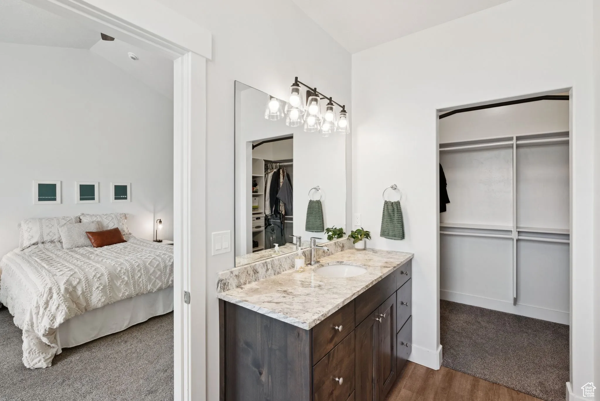 Bathroom with vanity, a spacious closet, ensuite bath, wood finished floors, and lofted ceiling