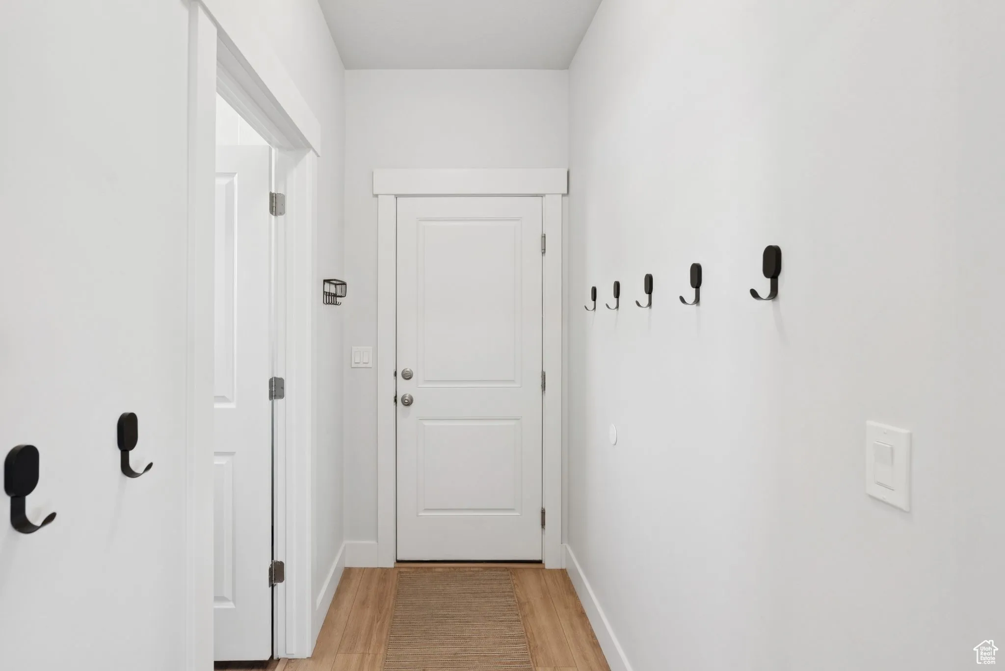 Doorway to outside with light wood finished floors and baseboards