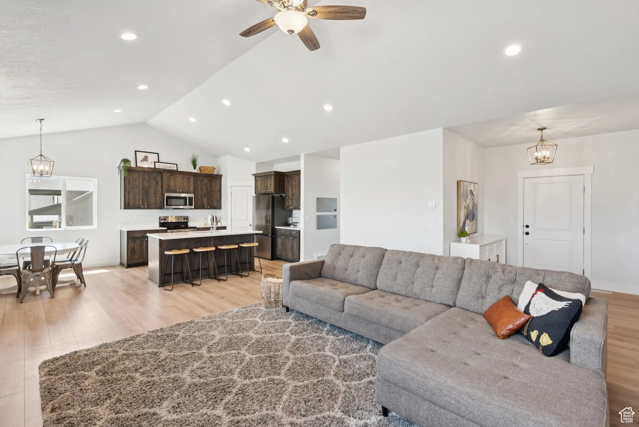 Living area featuring light wood finished floors, lofted ceiling, a chandelier, ceiling fan, and recessed lighting