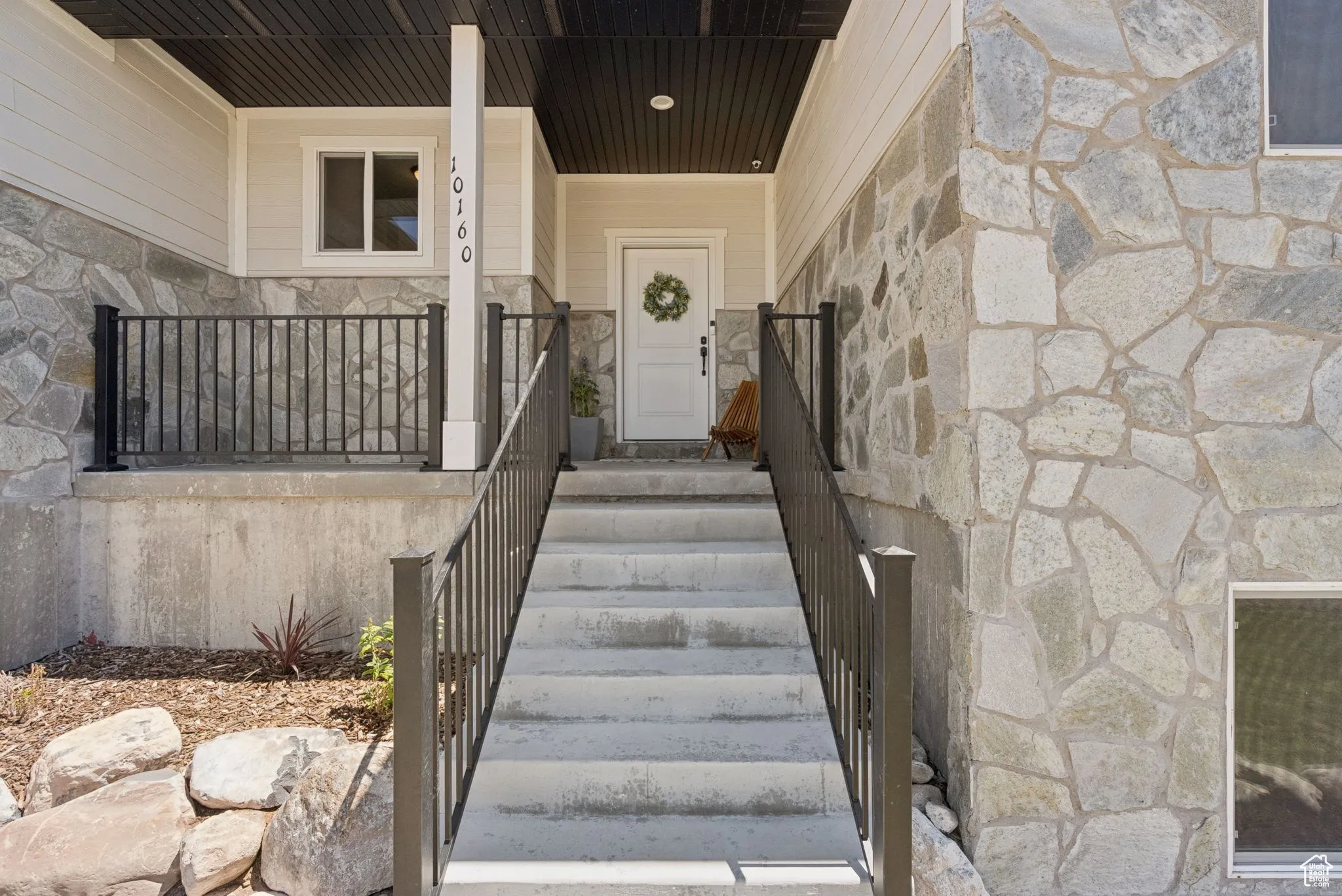 Property entrance featuring stone siding and covered porch