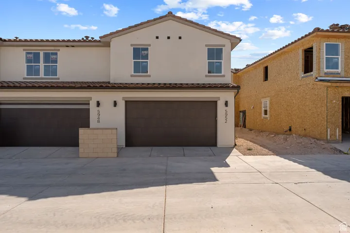 View of front of house featuring an attached garage, a tiled roof, concrete driveway, and stucco siding