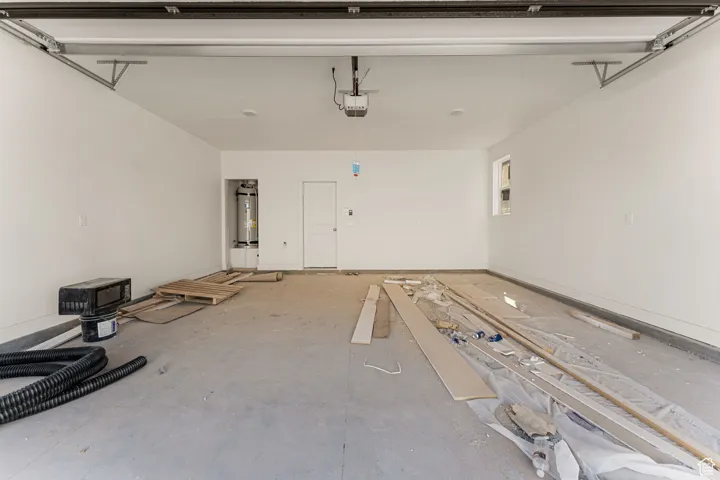 Garage featuring electric water heater and a garage door opener