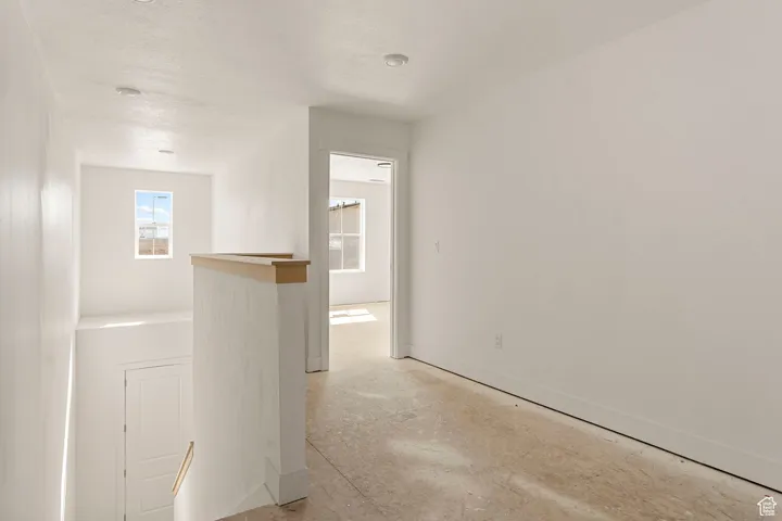 Hall featuring concrete floors and an upstairs landing