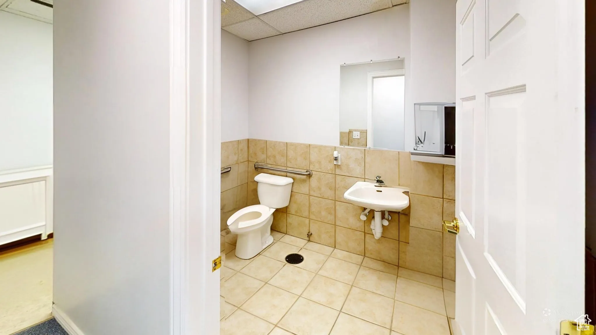 Bathroom with tile patterned flooring, a wainscoted wall, a paneled ceiling, and tile walls