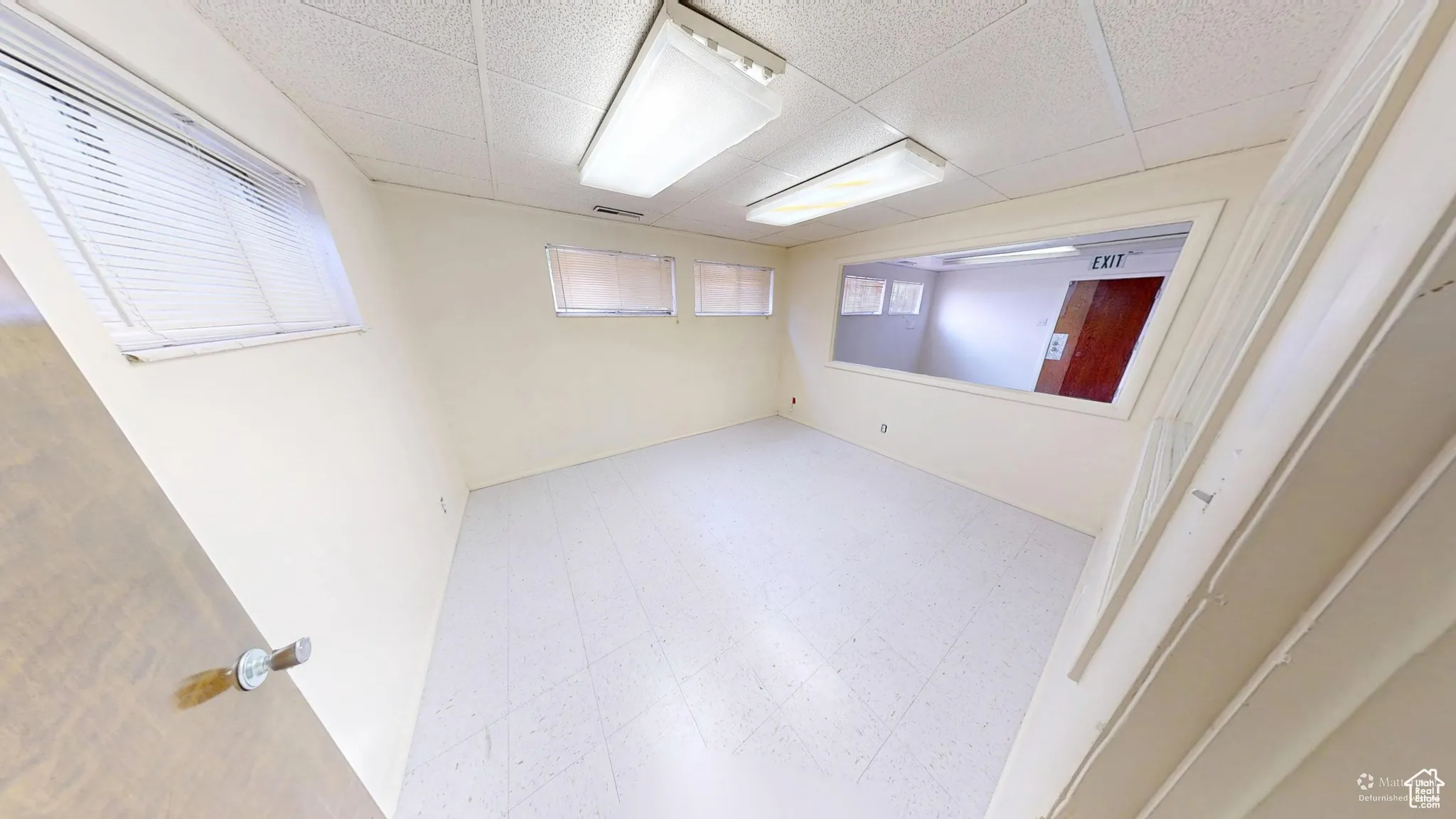 Empty room featuring tile patterned floors and a drop ceiling