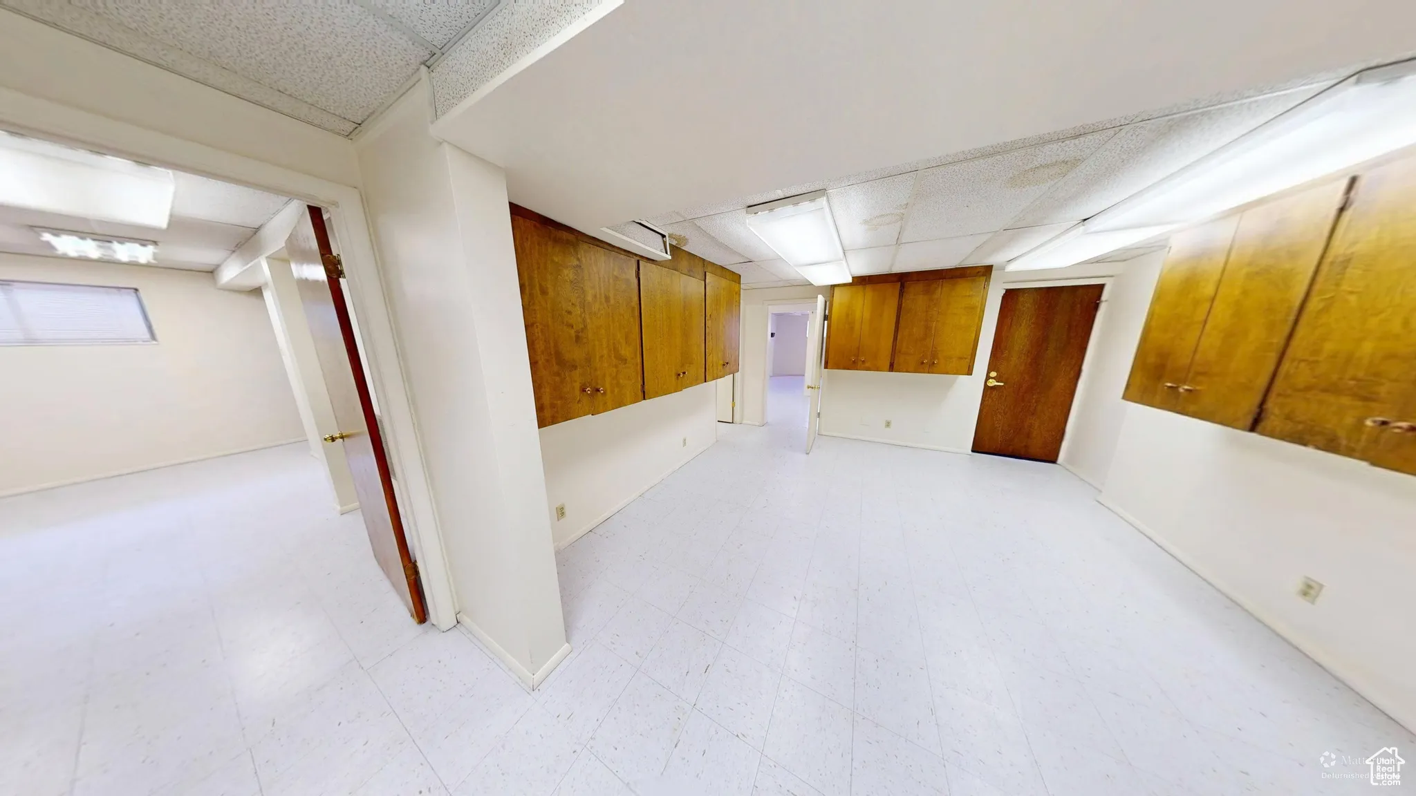 Finished basement featuring light flooring and a paneled ceiling