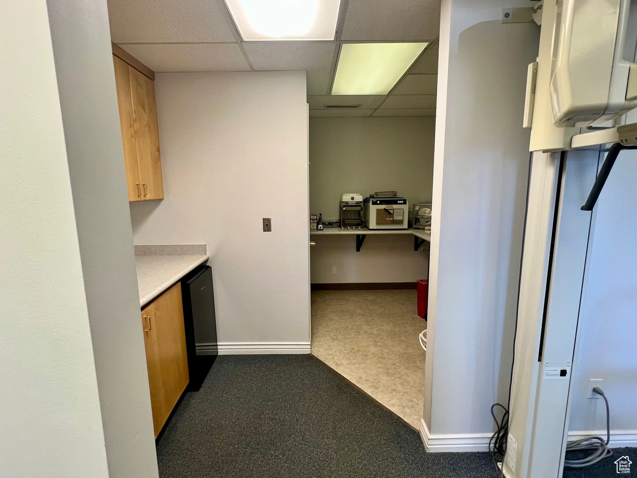 Kitchen with a paneled ceiling, dark carpet, and light countertops