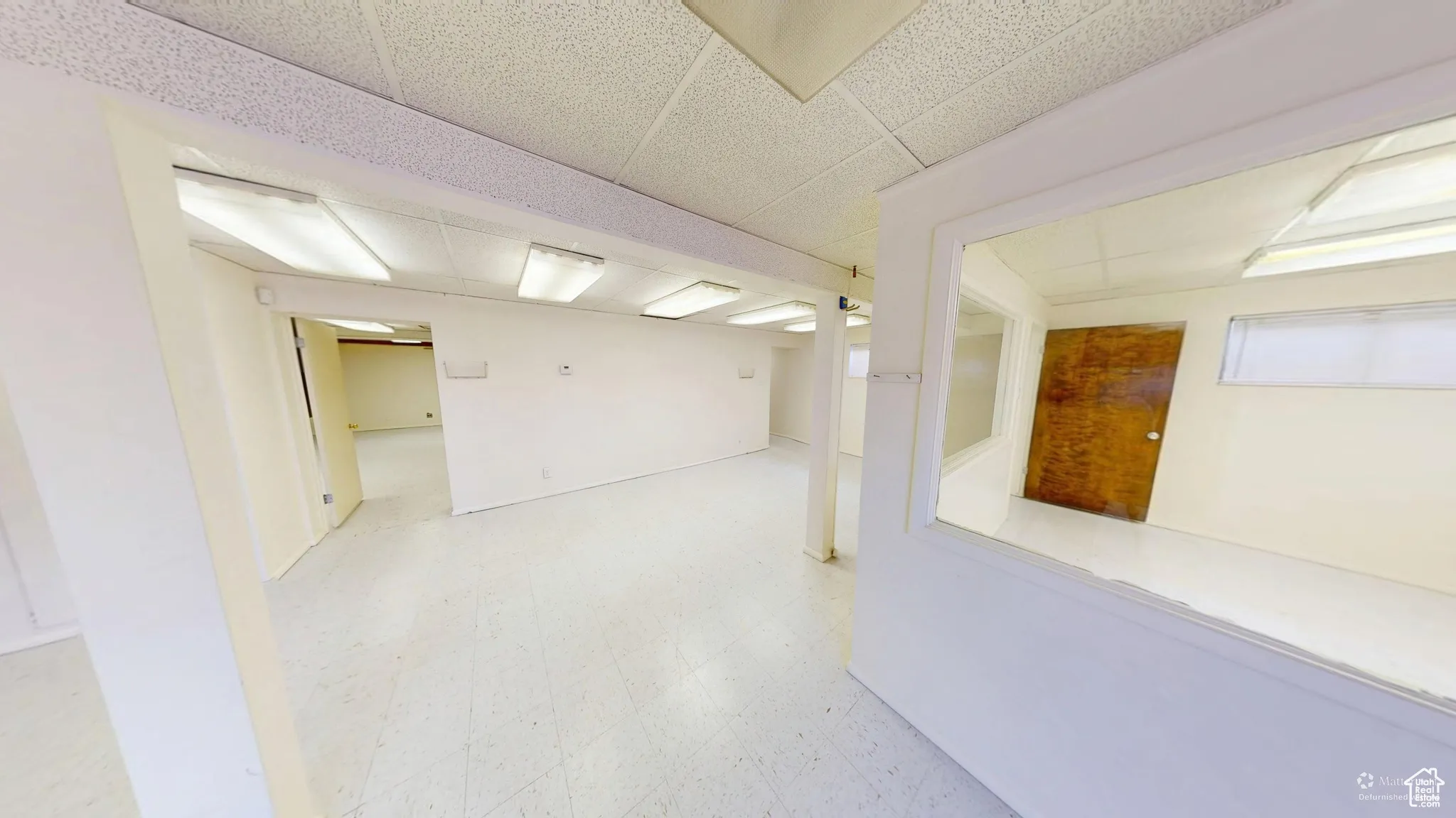 Finished below grade area featuring light flooring and a paneled ceiling