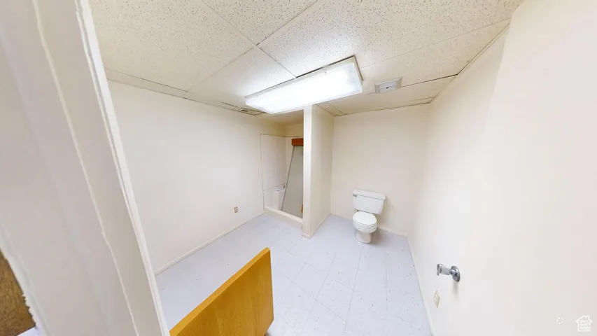 Bathroom featuring a drop ceiling, light flooring, and a stall shower