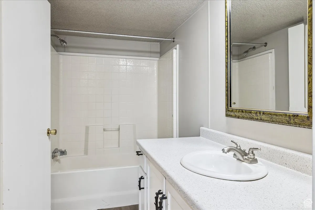 Bathroom with a textured ceiling, vanity, and  shower combination