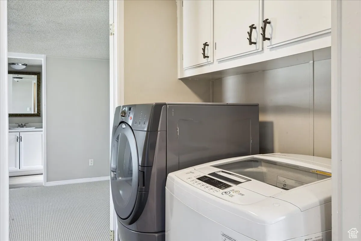 Laundry area featuring cabinet space, washing machine and clothes dryer, and a textured ceiling