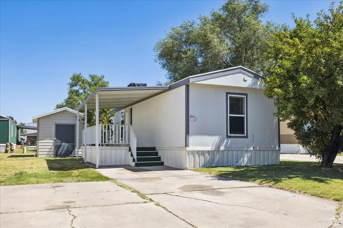 Manufactured / mobile home with a front yard, a storage unit, and a porch