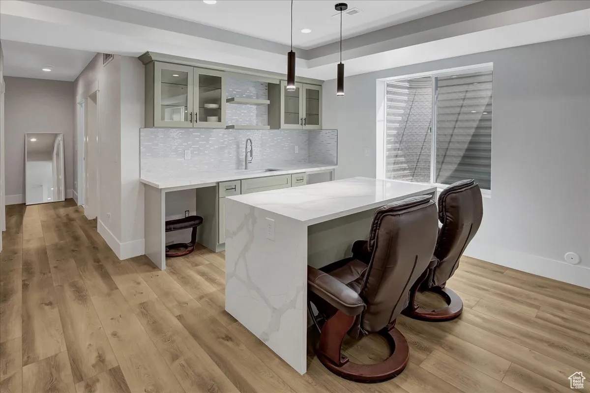 Bar with light wood finished floors, decorative light fixtures, decorative backsplash, and recessed lighting