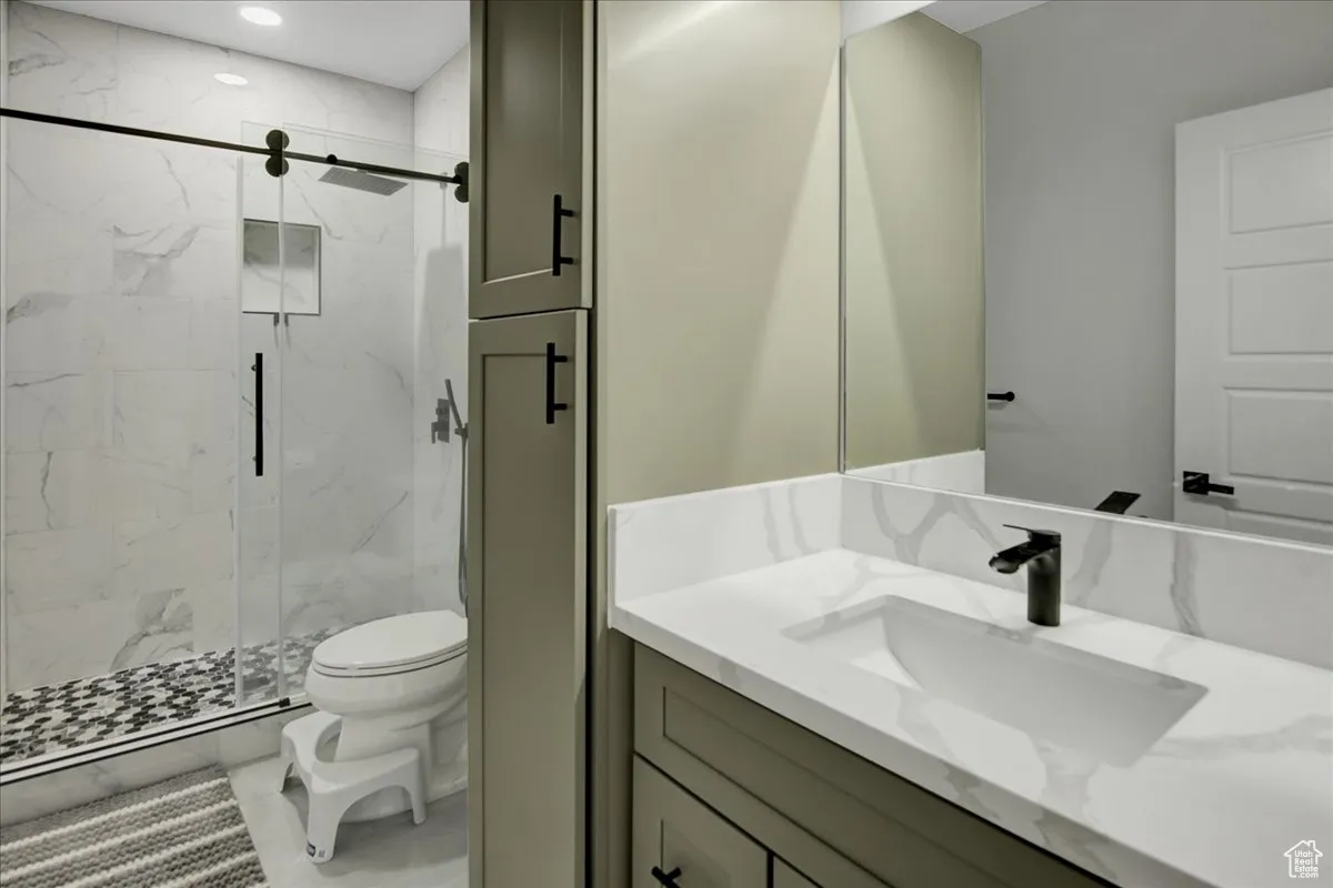Full bath featuring a marble finish shower, vanity, and recessed lighting