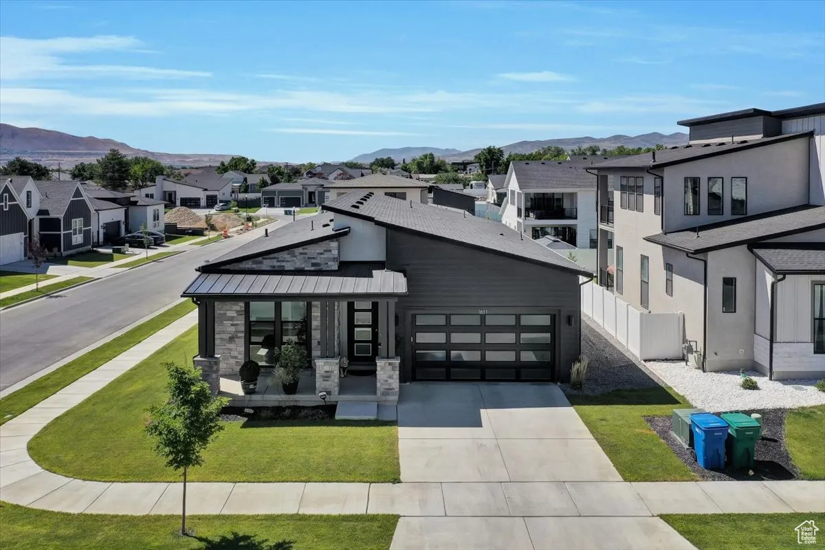 View of front of property featuring a residential view, driveway, stone siding, and a mountain view
