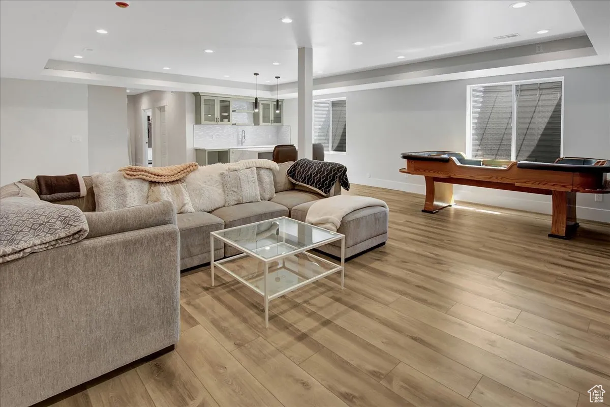 Living area with a raised ceiling, light wood-style floors, recessed lighting, and billiards