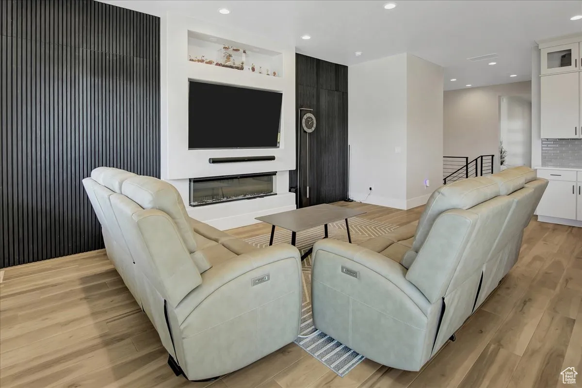 Living room featuring recessed lighting, light wood-style flooring, and a glass covered fireplace