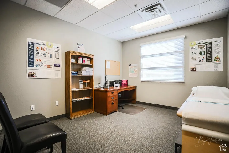 Carpeted home office with a paneled ceiling and baseboards