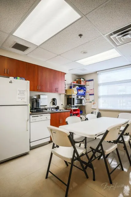 Kitchen with a paneled ceiling, white appliances, and dark countertops