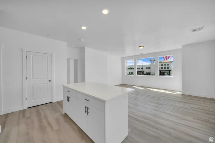 Empty room with light wood-style floors and recessed lighting