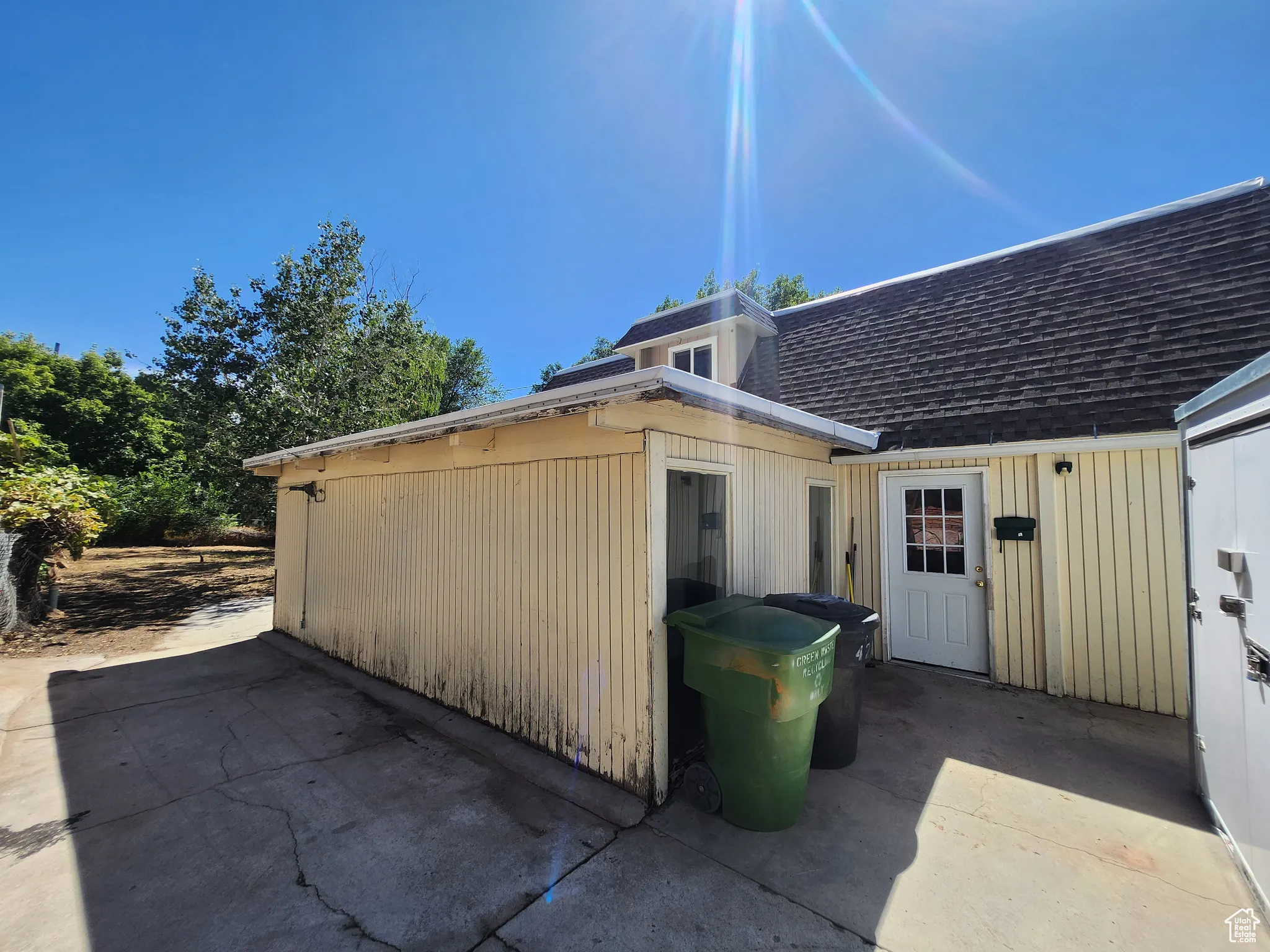View of property exterior with a shingled roof and a patio