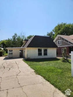 View of side of home with a yard, driveway, and a shingled roof