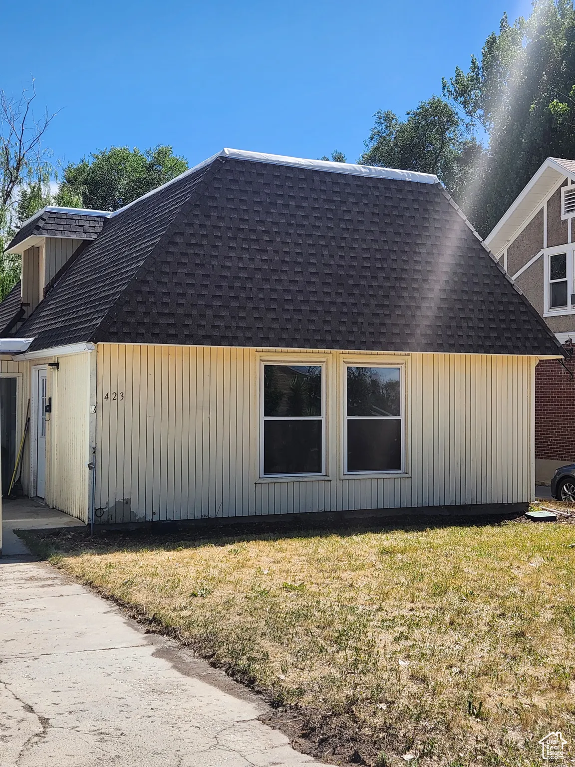 View of side of property with a shingled roof and a lawn