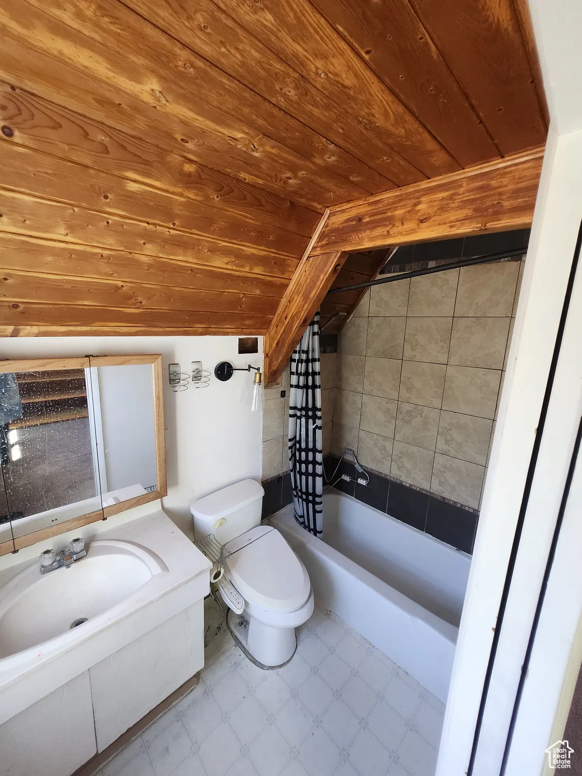 Full bathroom with tile patterned floors, shower / bath combo, vanity, and lofted ceiling